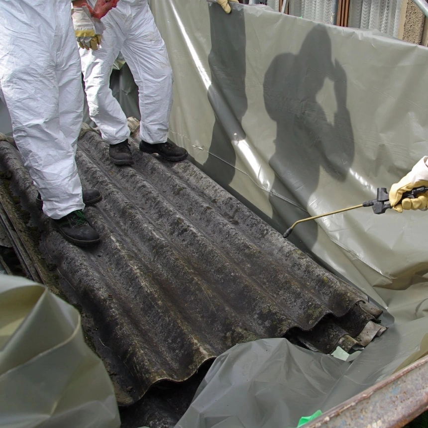 A man in white overalls standing next to a black tarp.