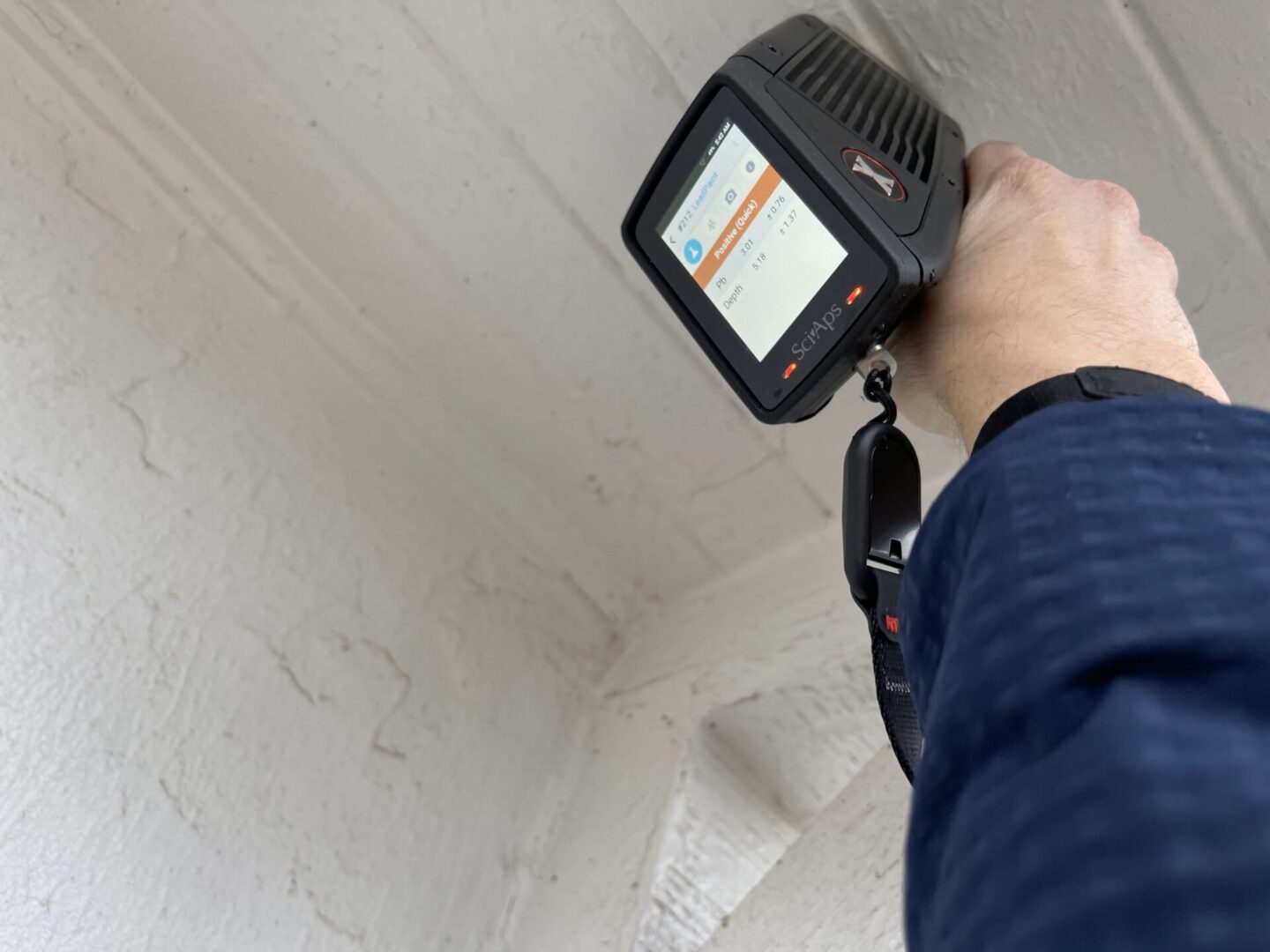 A person holding up a device to check the ceiling.