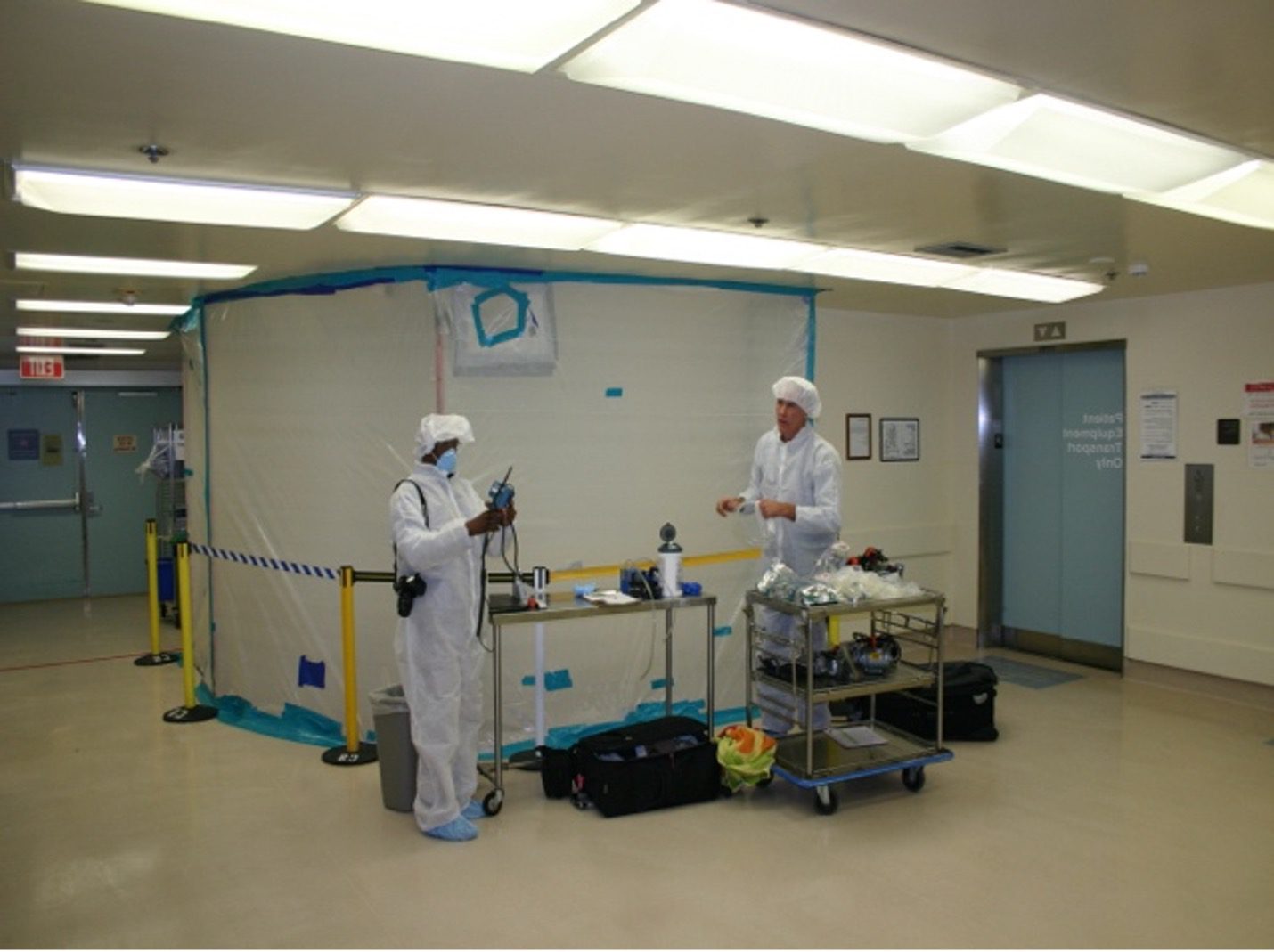 Two people in white suits and hats standing next to a room.