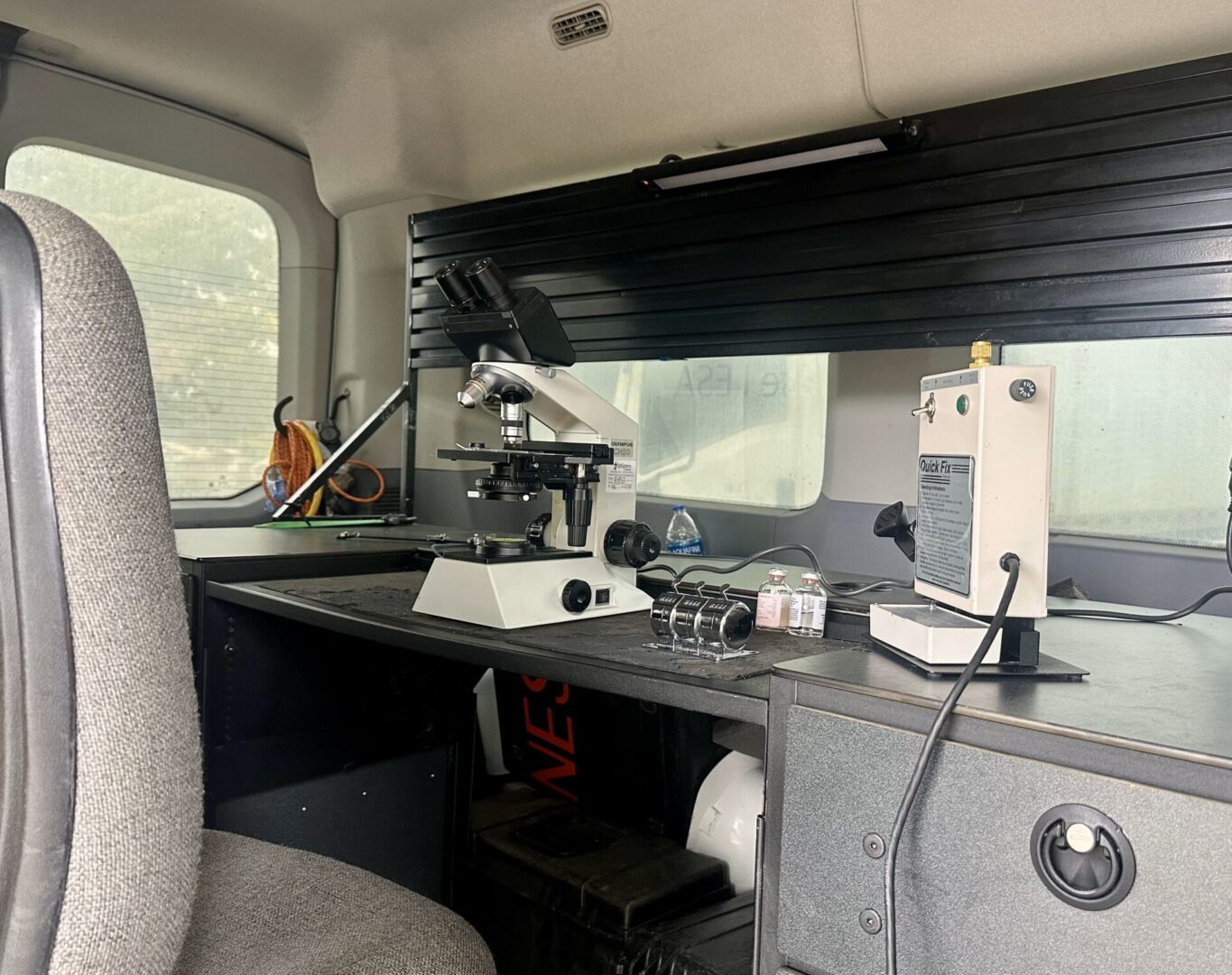 A desk with a microscope and other items on it.